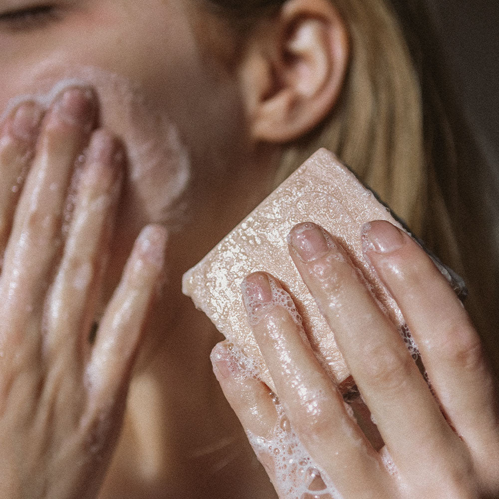 Detox solid cleansing bar being applied to woman&#39;s face showing suds