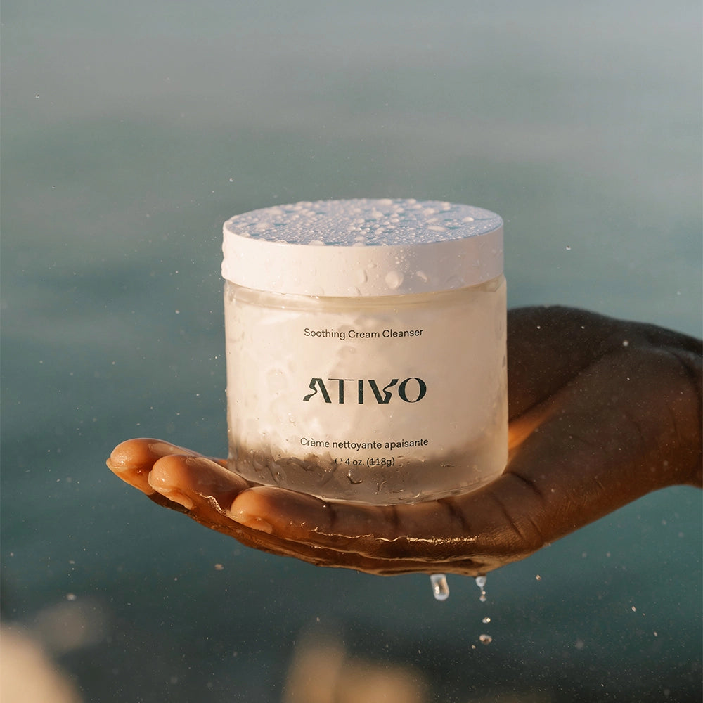 Soothing Cream cleanser, jar in hand with water dripping down against an ocean backdrop